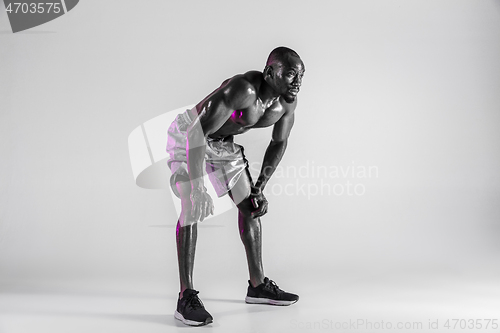 Image of Young african-american bodybuilder training over grey background