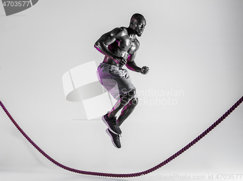 Image of Young african-american bodybuilder training over grey background