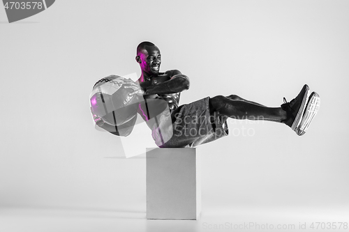 Image of Young african-american bodybuilder training over grey background