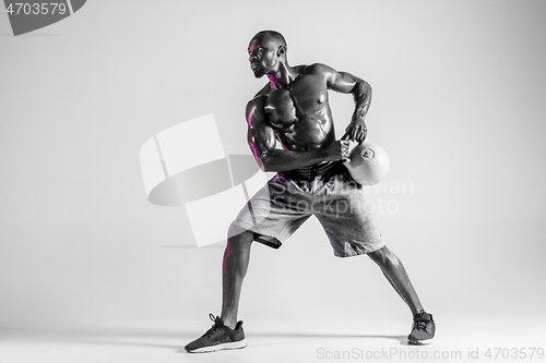 Image of Young african-american bodybuilder training over grey background