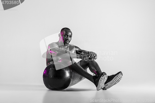 Image of Young african-american bodybuilder training over grey background