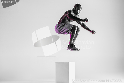 Image of Young african-american bodybuilder training over grey background