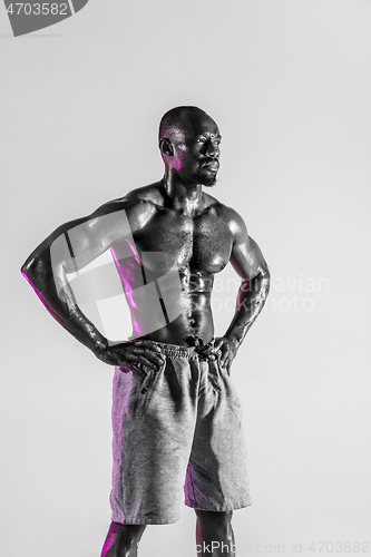 Image of Young african-american bodybuilder training over grey background