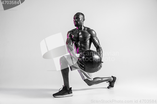 Image of Young african-american bodybuilder training over grey background