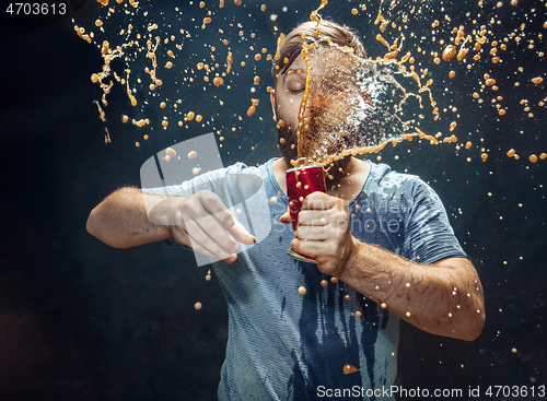 Image of Man drinking a cola and enjoying the spray.