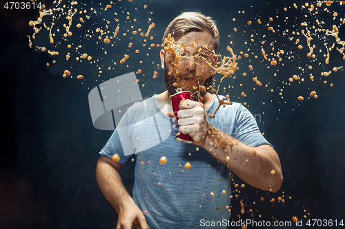 Image of Man drinking a cola and enjoying the spray.