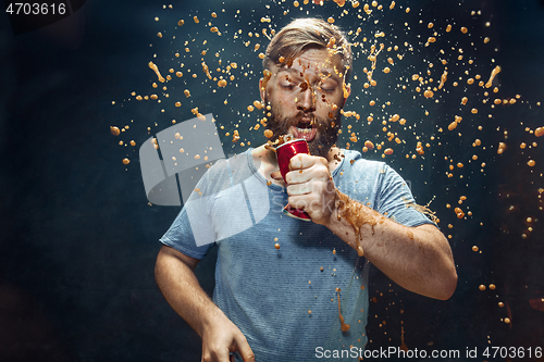 Image of Man drinking a cola and enjoying the spray.