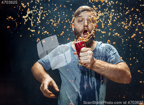 Image of Man drinking a cola and enjoying the spray.