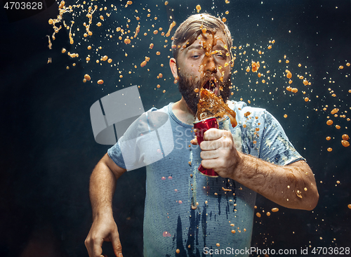 Image of Man drinking a cola and enjoying the spray.