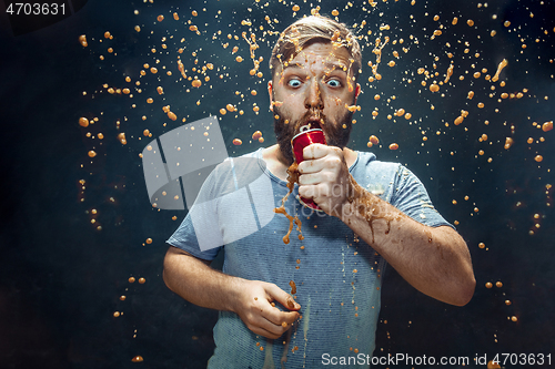 Image of Man drinking a cola and enjoying the spray.