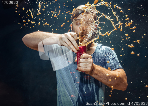 Image of Man drinking a cola and enjoying the spray.