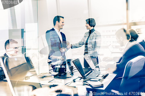 Image of Confident business people shaking hands in moder corporate office.