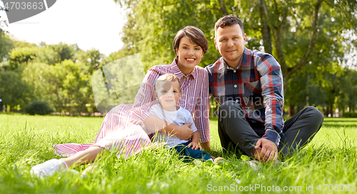 Image of happy family at summer park sitting on grass