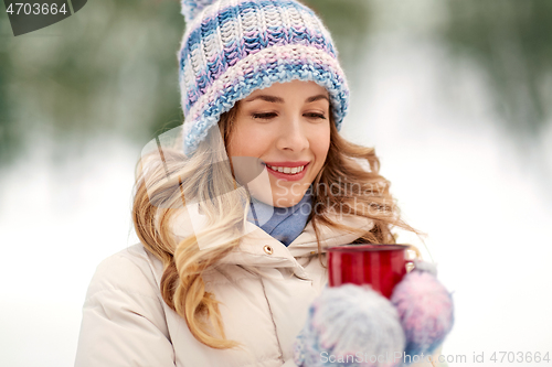 Image of happy young woman with tea cup outdoors in winter