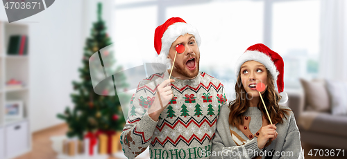 Image of couple with christmas party props in ugly sweaters