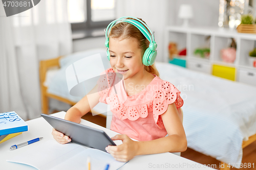 Image of girl in headphones with tablet computer at home