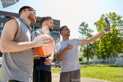 Image of happy men taking selfie on basketball playground