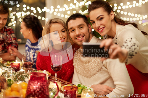 Image of friends having christmas dinner and taking selfie