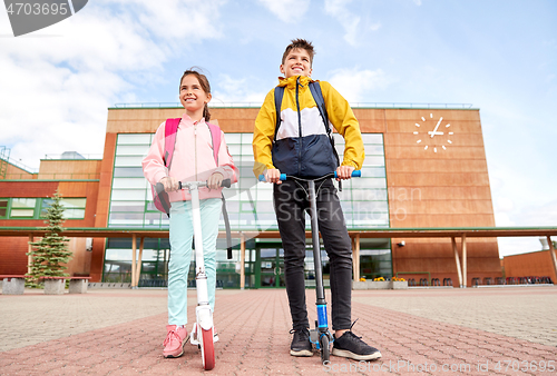 Image of happy school children with backpacks and scooters