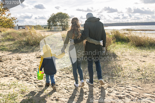 Image of happy family walking along autumn beach