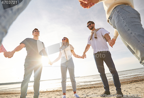 Image of happy friends holding hands on summer beach