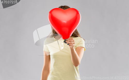 Image of woman covering face with heart-shaped balloon