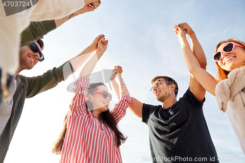 Image of happy friends holding hands on summer beach