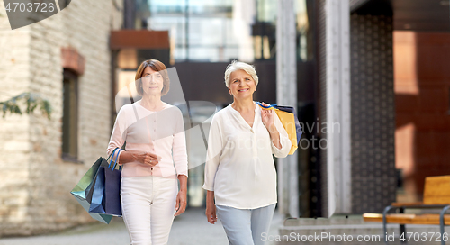 Image of senior women with shopping bags walking in city