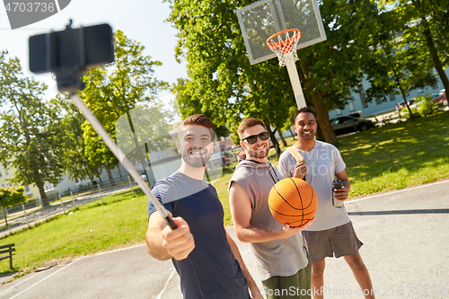 Image of happy men taking selfie on basketball playground