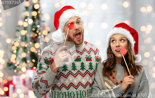 Image of couple with christmas party props in ugly sweaters