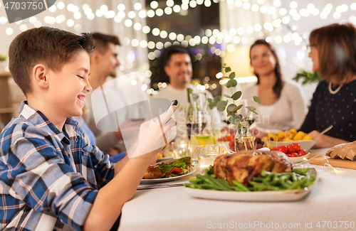 Image of boy with smartphone at family dinner party