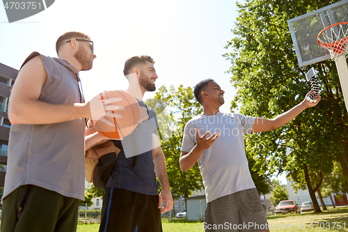 Image of happy men taking selfie on basketball playground