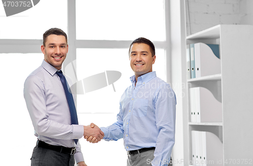 Image of happy businessmen making handshake at office