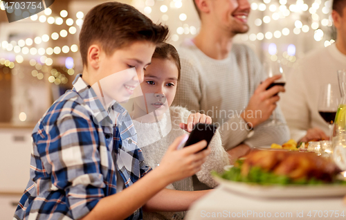 Image of boy with sister using smartphone at family dinner