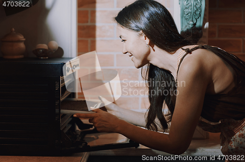 Image of Staying at home woman drying flaxseeds in the modern oven