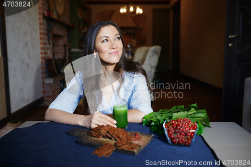 Image of Smiling vegetarian woman sitting at the table with celery fresh 