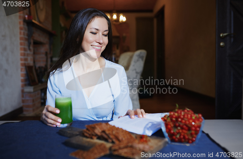 Image of Smiling vegetarian woman sitting at the table with celery fresh 