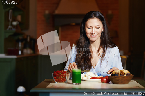 Image of Smiling vegetarian woman sitting at the table and eating healthy