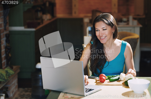 Image of Woman at the table with vegetables working via laptop