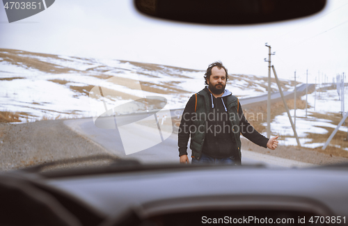 Image of Traveller on the rural road trying to stop a car for assistance