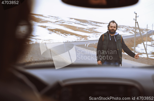 Image of Traveller on the rural road trying to stop a car for assistance