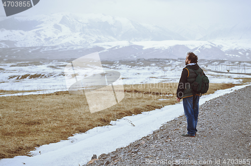 Image of Touris wearing backpack and standing at the rural road while loo