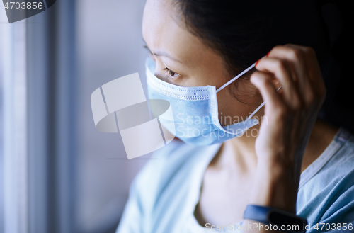 Image of Woman staying at home wearing protective surgical mask