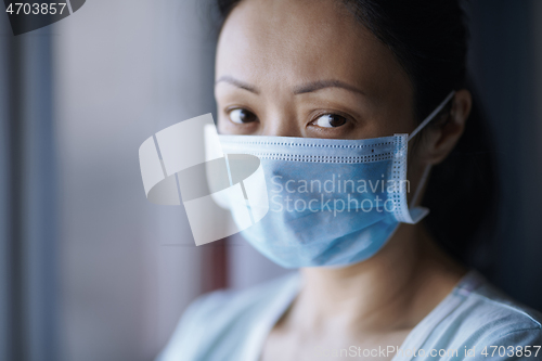 Image of Woman staying at home wearing protective surgical mask