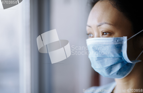 Image of Woman staying at home wearing protective surgical mask
