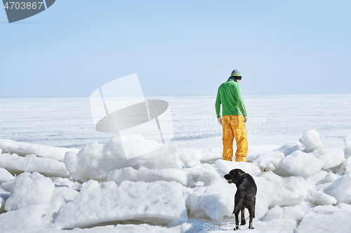 Image of Young adult man outdoors with his dog exploring winter landscape