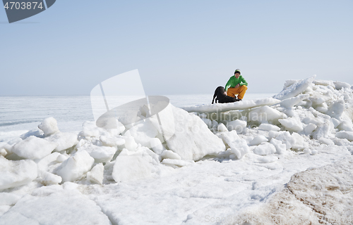 Image of Young adult man outdoors with his dog having fun in winter lands