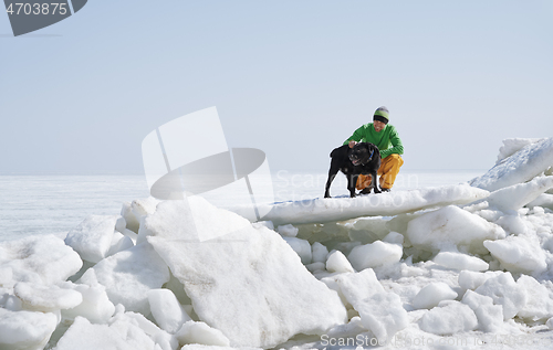 Image of Young adult man outdoors with his dog having fun in winter lands