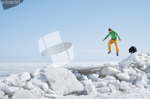 Image of Young adult man outdoors with his dog having fun in winter lands