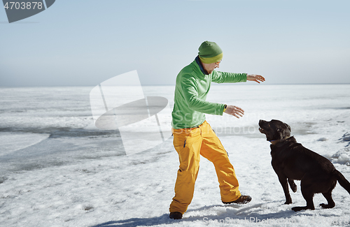 Image of Young adult man outdoors with his dog having fun in winter lands